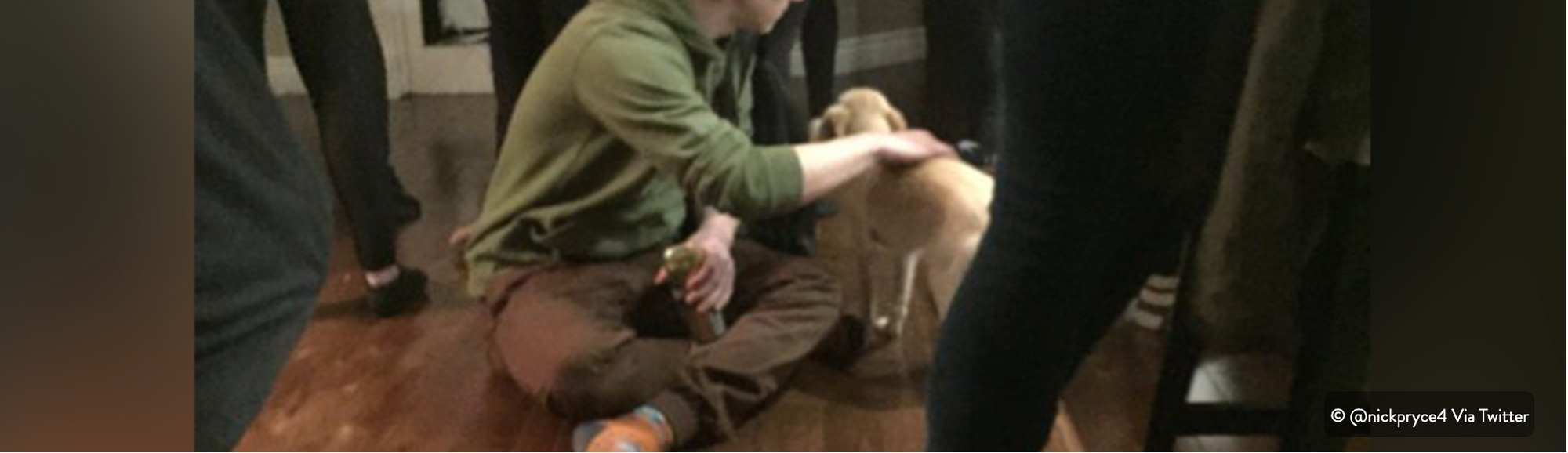 Man sitting crosslegged on the floor petting a dog