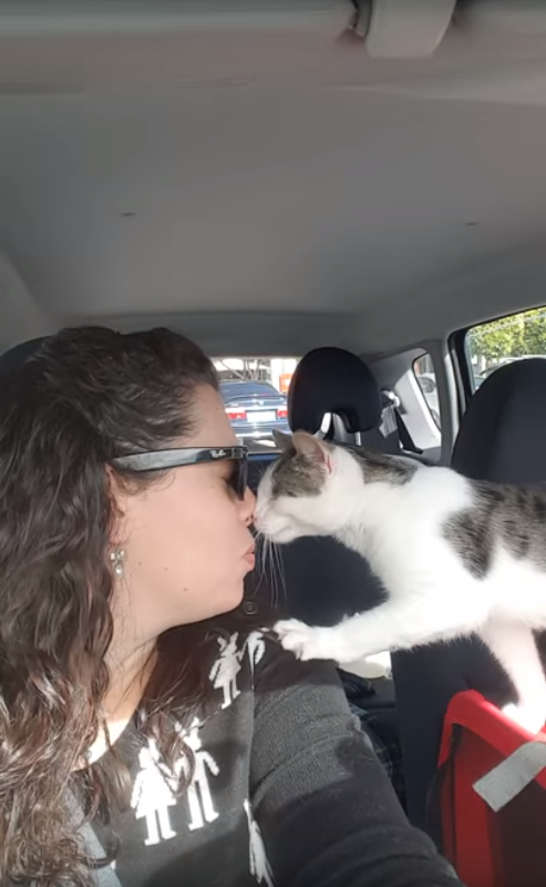 Woman kissing her cat on the nose in her car