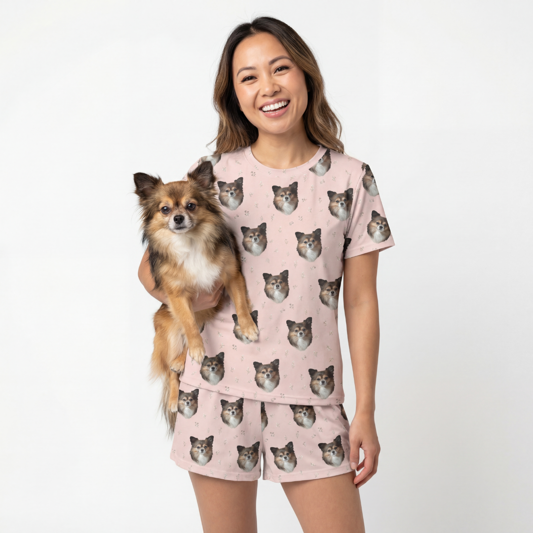 Woman wearing a pink pajama set with dog patterns, holding a small dog[BlushBlossoms]