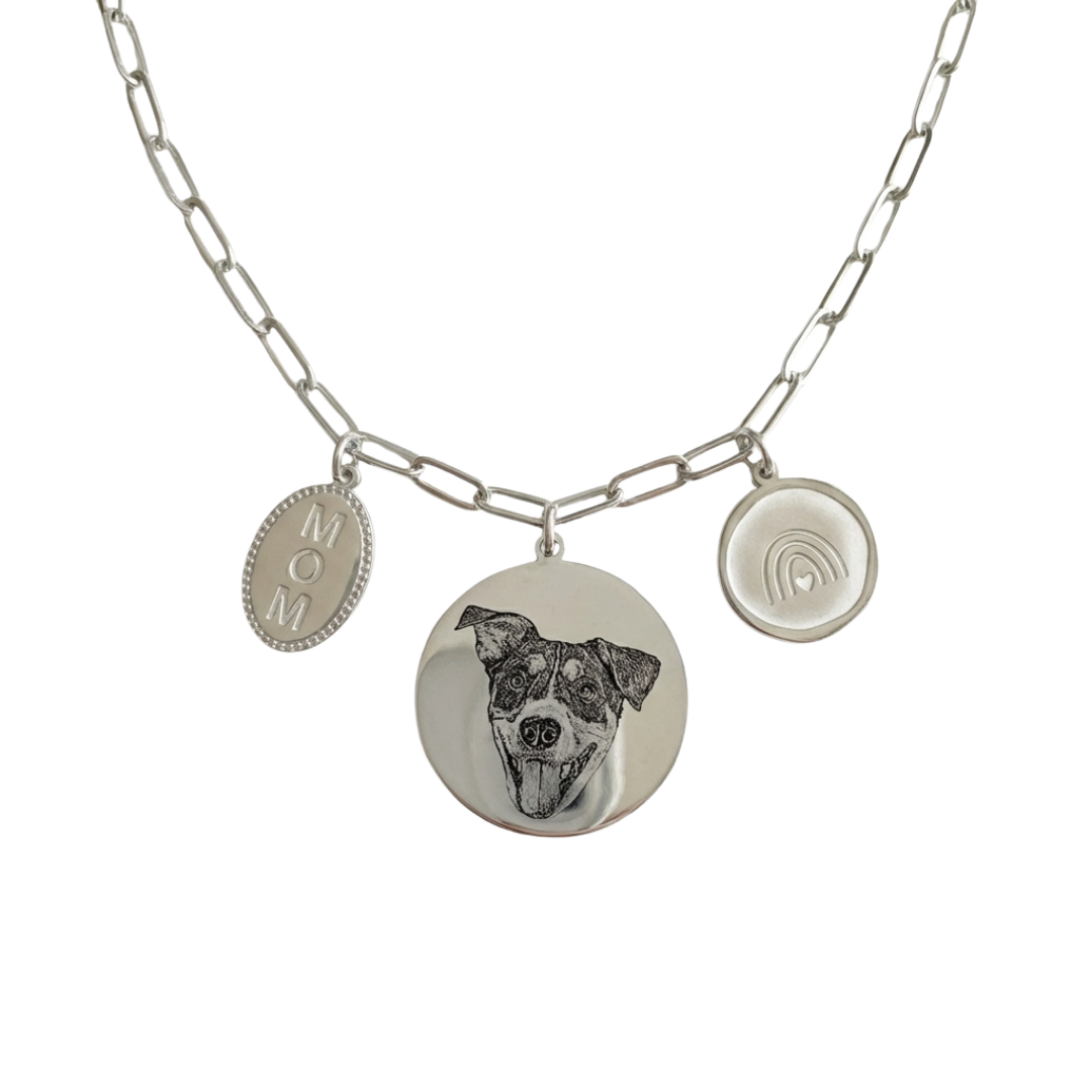 Silver necklace with a dog portrait charm and 'MOM' tag on a white background