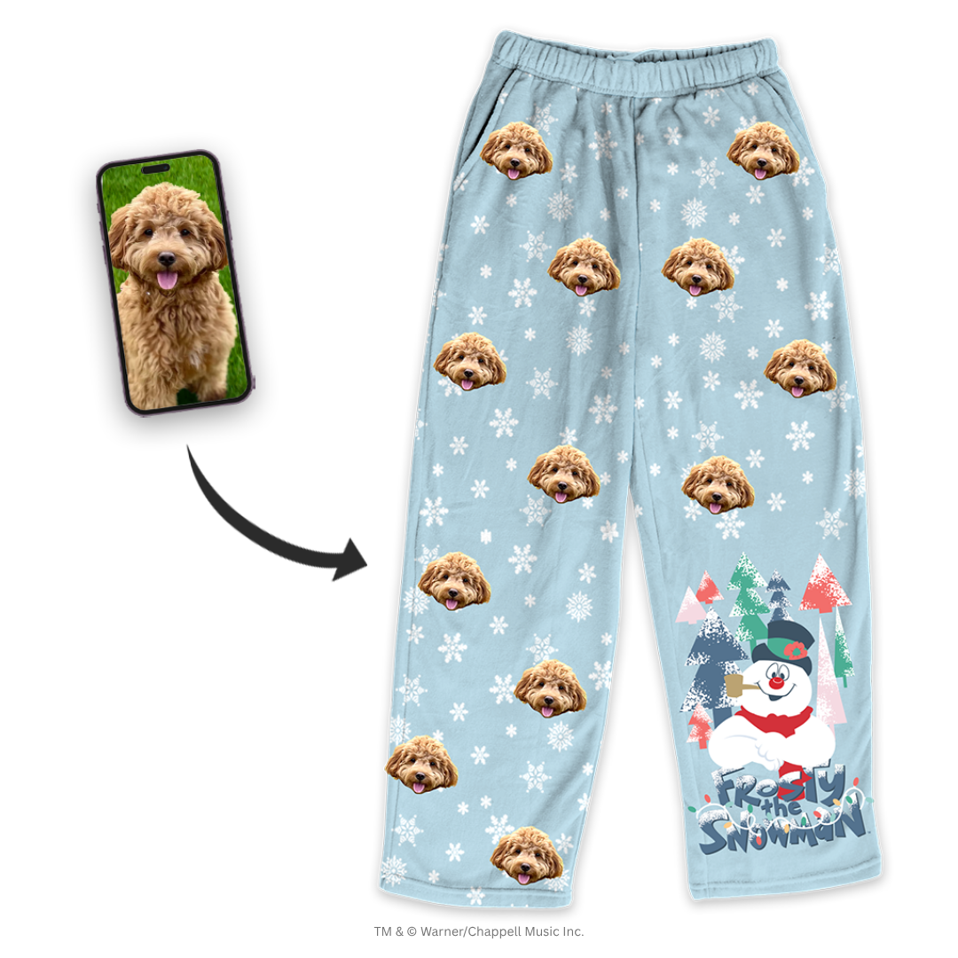 Light blue pajama pants featuring a repeating dog's face pattern and white snowflakes, shown next to a smartphone displaying the same dog's photo and a Frosty the Snowman graphic.