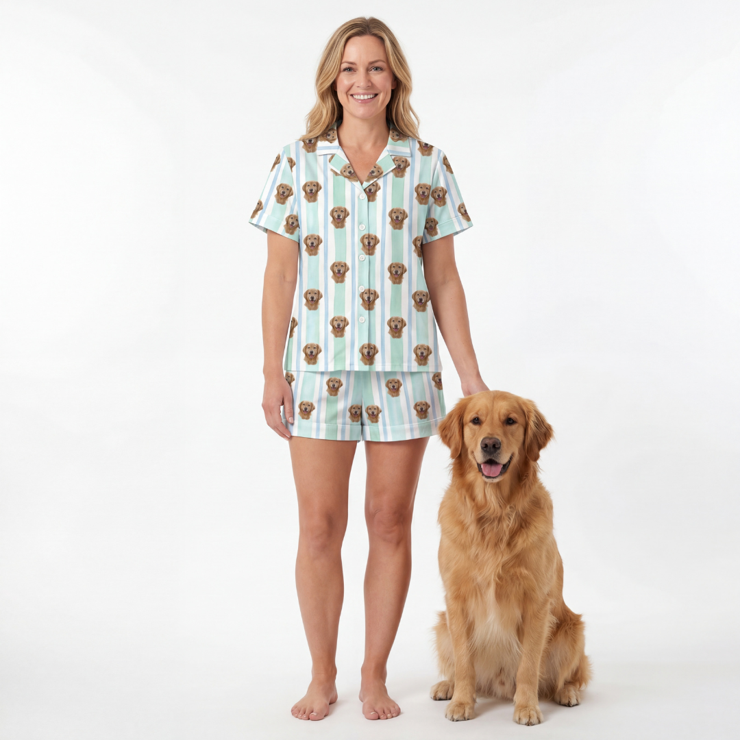 Woman wearing a short button down pajama set with dog pattern standing next to a golden retriever on a white background[MintStripes]