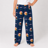 A person wearing navy blue Christmas-themed lounge pants with a repeating print of the Grinch in a Santa hat, shown against a plain light gray studio background.