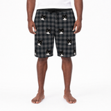Person wearing black and gray plaid shorts with cat prints on a white background
