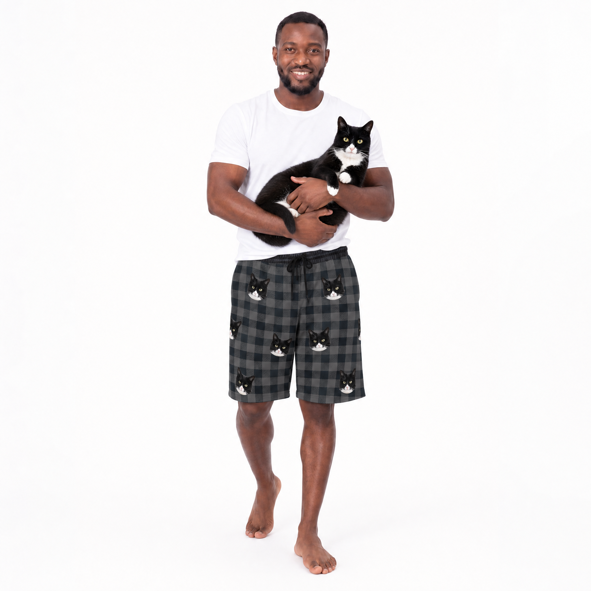 Man holding a cat wearing a white t-shirt and checkered shorts with cat designs on a white background