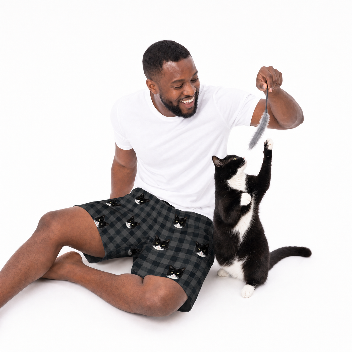 Man playing with a cat using a toy on a white background