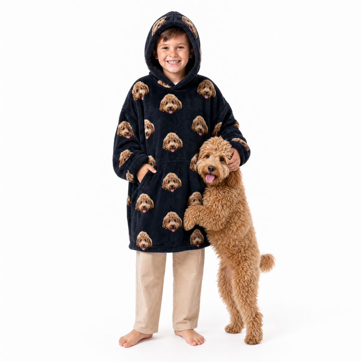 Child wearing a black blanket hoodie with dog pattern, standing next to a dog on a white background