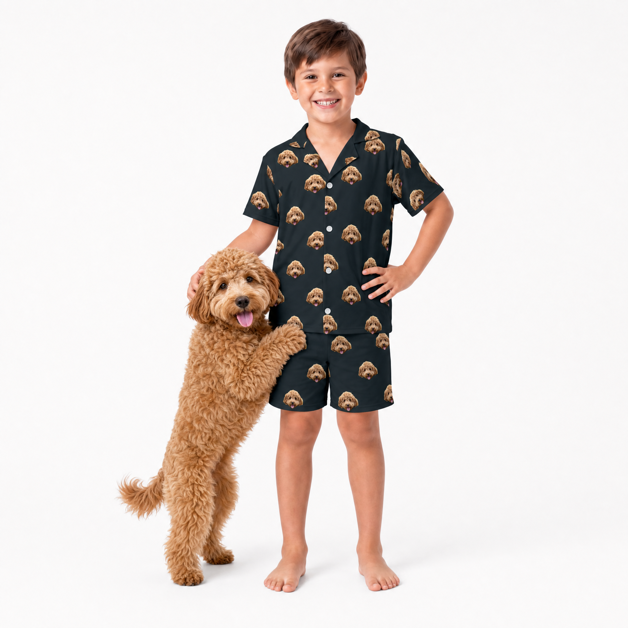 Child wearing a black pajama set with dog pattern, standing next to a brown dog on a white background