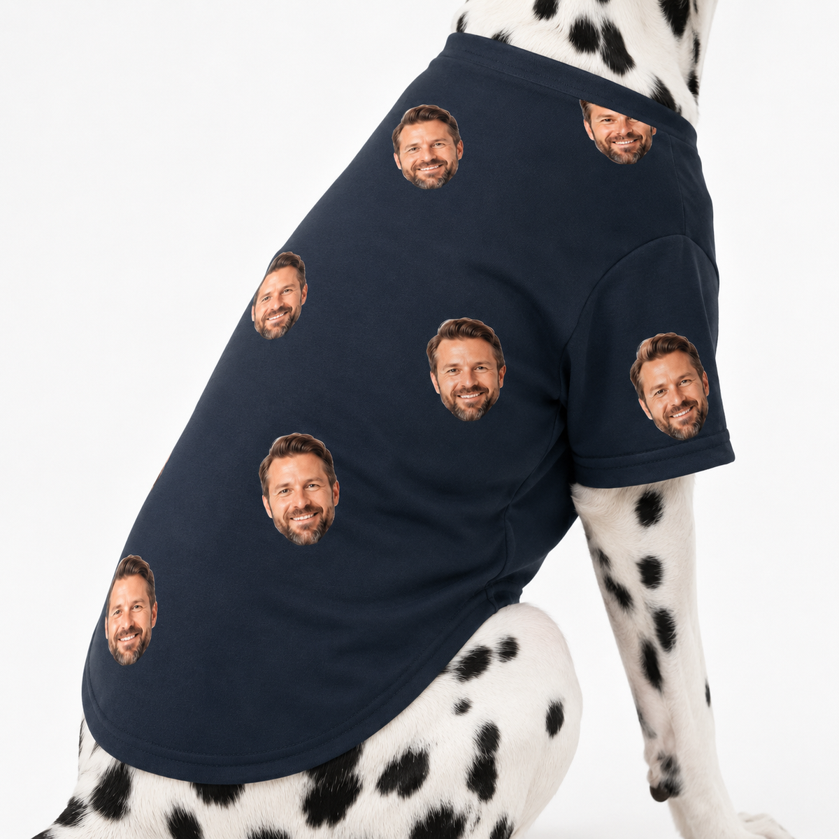Dalmatian wearing a black custom dog shirt with a repeating face pattern on a white studio background.