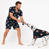 Man and Dalmatian wearing matching black custom pet pajamas with a repeating dog face pattern.