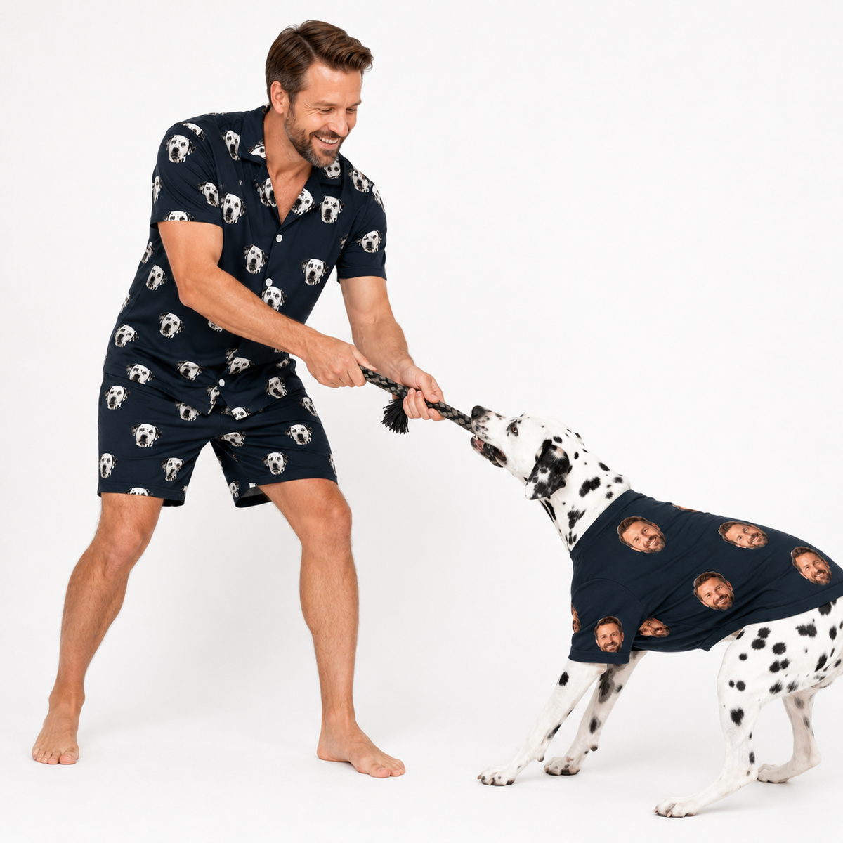 Man and Dalmatian wearing matching black custom pet pajamas with a repeating dog face pattern.