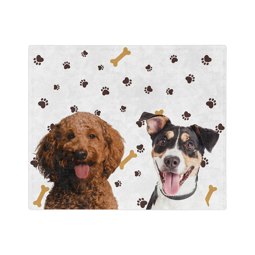 White blanket with paws and bones featuring the portraits of two dogs.