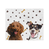 White blanket with paws and bones featuring the portraits of two dogs.