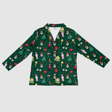 A long-sleeve collared shirt with a festive Christmas village print on a dark green background, featuring Boston Terrier dogs, Christmas trees, bells, houses, and flags.