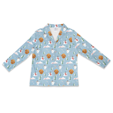 A long-sleeve button-up shirt in light blue, featuring an all-over Christmas-themed print with golden retriever dogs, snowmen, Christmas trees, and snowflakes.