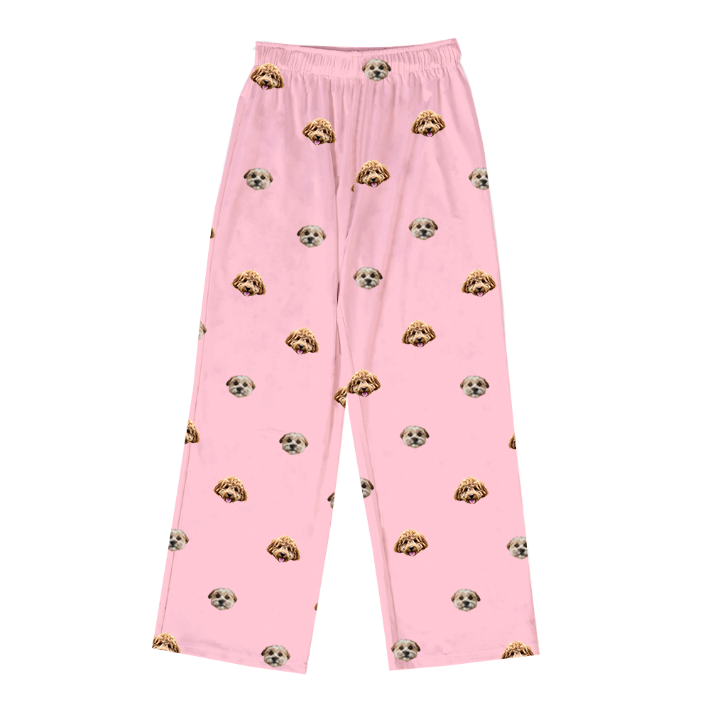 Pink pajama pants with elastic waistband, featuring a scattered pattern of realistic doodle dog faces in tan, cream, and brown colors.
