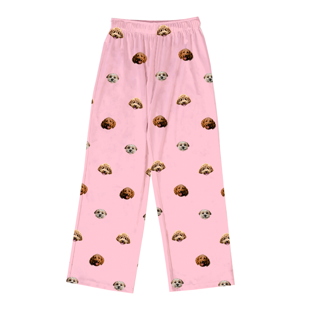 Pink pajama pants with elastic waistband, featuring a scattered pattern of realistic doodle dog faces in brown, tan, and cream colors.