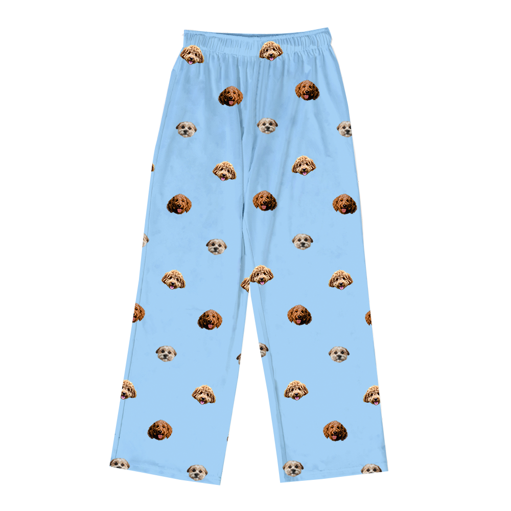 A pair of full-length pajama pants in light sky blue. The pants feature a repeating pattern of realistic photos of three different dogs' heads.