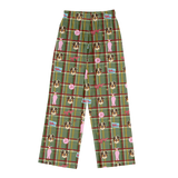 Green plaid lounge pants with a repeating pattern of French Bulldog illustrations, pink silhouettes of women, and small red and blue signs, shown on a plain white background.
