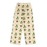 A pair of cream-colored pajama pants featuring an all-over Christmas print of green cacti, Santa Claus, candy canes, and snowflakes, displayed flat against a white background.