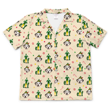 A short-sleeve button-up camp shirt in a warm cream color, featuring an all-over festive print of Dalmatian dogs dressed as elves, candy canes, and paw prints.