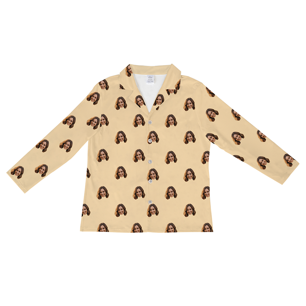 Long-sleeved, button-down pajama shirt in a solid buttery yellow or pale tan color, featuring a repeating pattern of a smiling woman's face with brown hair.
