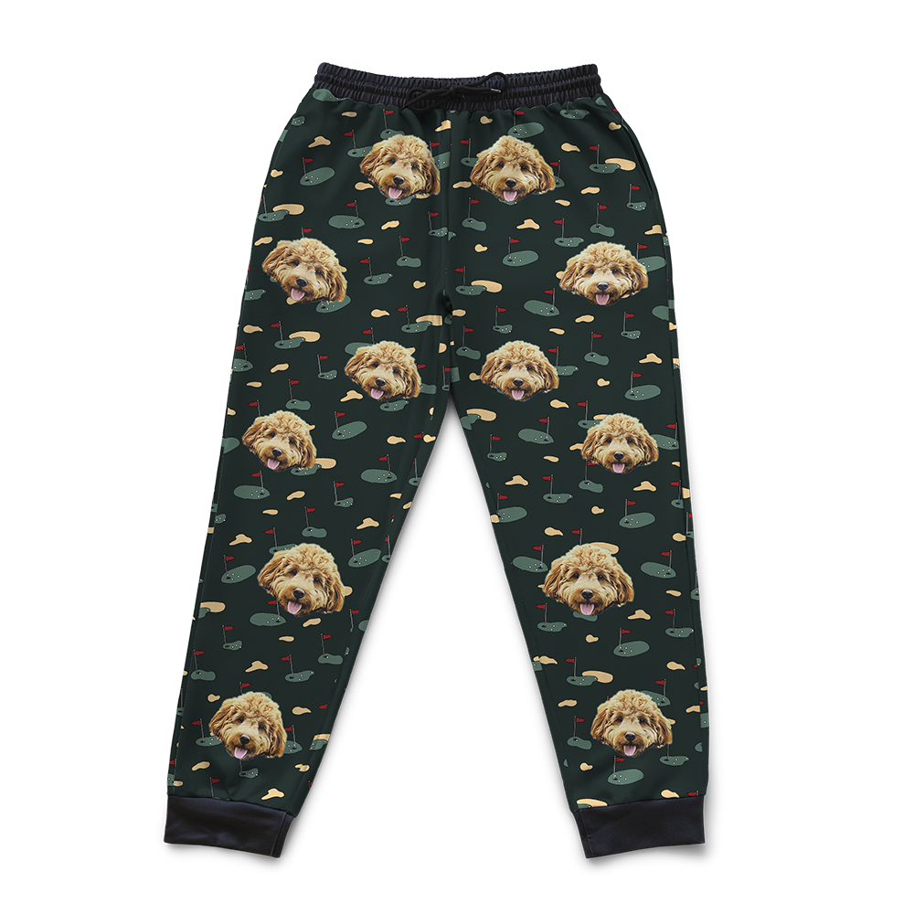Black jogger sweatpants featuring a repeating pattern of a smiling fluffy dog’s face with the phrase ‘I Love Mom’ in white text and small heart icons across the fabric.