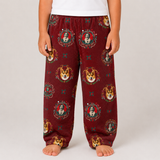 A child wearing burgundy fleece pants with a repeating print of Santa Muerte and corgis, paired with a white t-shirt, shown against a light gray studio background.