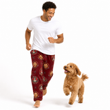 A man wearing a white t-shirt and burgundy pajama pants with a dog print pattern, running barefoot next to a small golden dog on a white background.