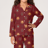 A child wearing a matching long-sleeve button-front pajama top and pants set in burgundy red with an allover printed pattern of golden retriever dog faces in circular frames, photographed against a light gray studio background.