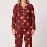 A woman wearing a matching long-sleeve button-front pajama top and pants set in a deep burgundy red, featuring an all-over print of golden retriever dog heads with colorful crest-style details. The photo is taken against a plain light gray studio background.