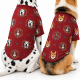 Two dogs wearing matching red graphic pet shirts with a repeating print of dog portraits and decorative frames, photographed on a clean white studio background.