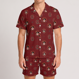 A man wearing a matching short-sleeve button-up pajama shirt and shorts set in a deep burgundy color, featuring an all-over print of cartoon dog faces inside circular frames, against a light gray studio background.