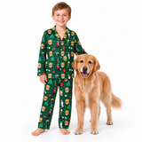 A young boy wearing a green Christmas-themed pajama set with a lion print stands barefoot next to a golden retriever dog on a solid white background.