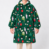 A person wearing a dark green hooded sweatshirt with an all-over festive print of black-and-white cat faces, red Santa hats, pink pajamas, Christmas trees, houses, and small holiday icons, photographed against a light gray studio background.