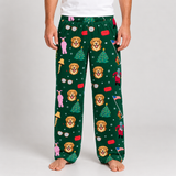 A person wearing dark green holiday lounge pants with a repeating print of golden retriever faces, Christmas trees, bells, flags, and small figures, shown against a light gray studio background.