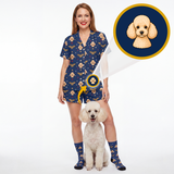 A woman modeling a navy blue short-sleeve scrub-style romper and matching socks with a dog print, standing next to a small white poodle. A circular inset shows a close-up of the dog face motif on the fabric.