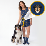 A woman wearing a navy blue sleeveless top and matching shorts with a small dog print, standing next to an Australian Shepherd. A circular inset shows a close-up of a dog portrait on the navy background with a yellow border.