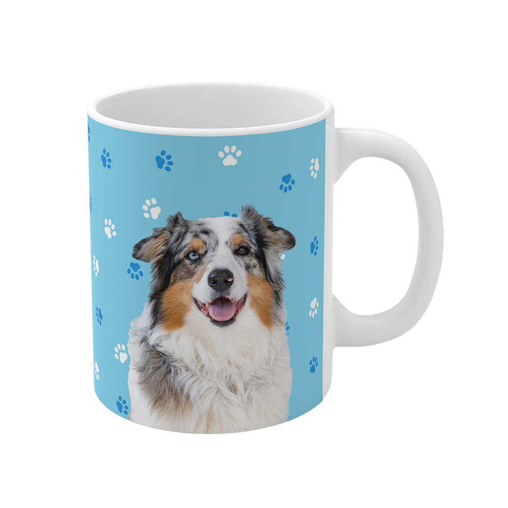 Light blue ceramic mug with paws pattern, featuring a smiling, multicolored Australian Shepherd