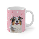 Pink ceramic mug with paws pattern featuring a smiling, multicolored Australian Shepherd