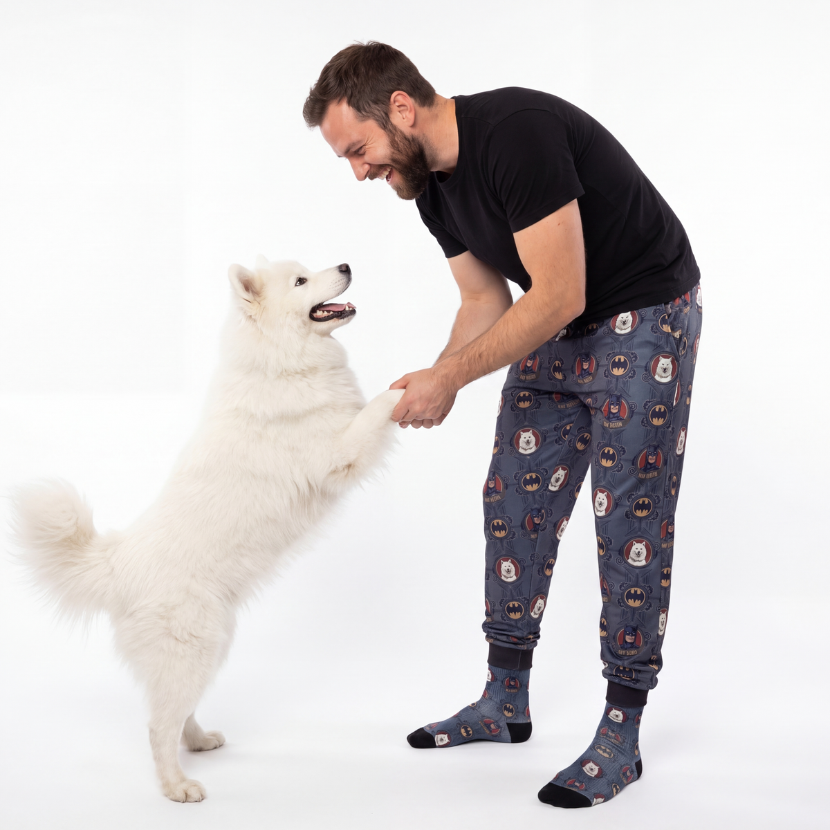 Man in patterned pajama pants interacting with a white dog on a white background