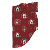 A folded red fabric item, likely a blanket or towel, featuring a repeating pattern of Dalmatian dog portraits, butterflies, and decorative frames with small portrait illustrations.
