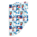 A folded blanket or towel featuring a festive holiday print with cartoon dogs in red scarves, snowmen, snow globes, and snowflakes on a white and blue background.