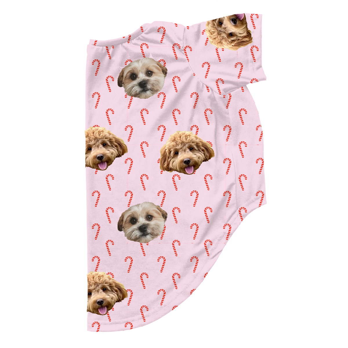 Pink dog pajamas decorated with a candy cane pattern and custom printed faces of two small dogs, shown on a flat lay.