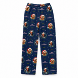 A pair of navy blue Christmas-themed pajama pants featuring a repeating pattern of a golden dog in a Santa hat, surrounded by green holly leaves and white snowflakes, with the text 'CHRISTMAS WOODS'.