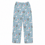 Light blue pajama pants with an all-over Christmas dog print, featuring dogs in snow, snowmen, evergreen trees, and snowflakes, shown flat on a white background.