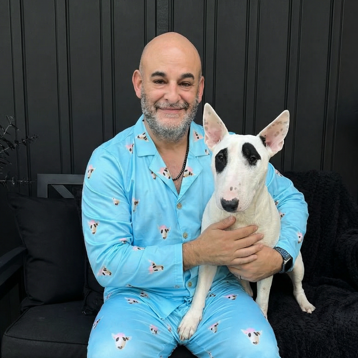 Man in blue pajamas holding a white dog