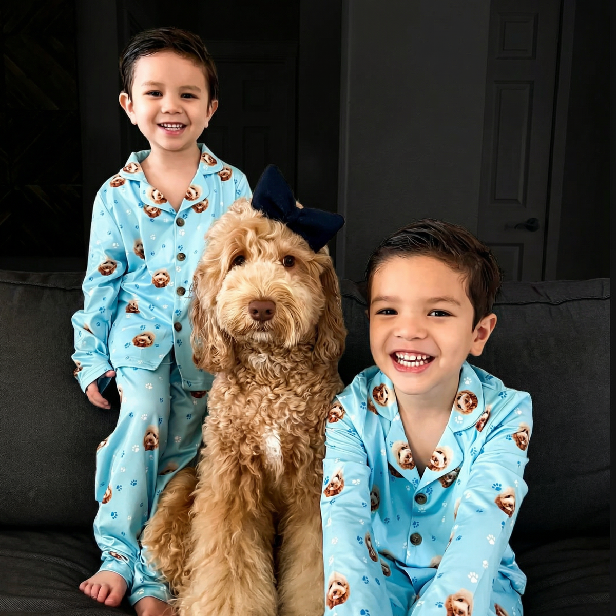 Two children in matching pajamas with a dog on a dark background
