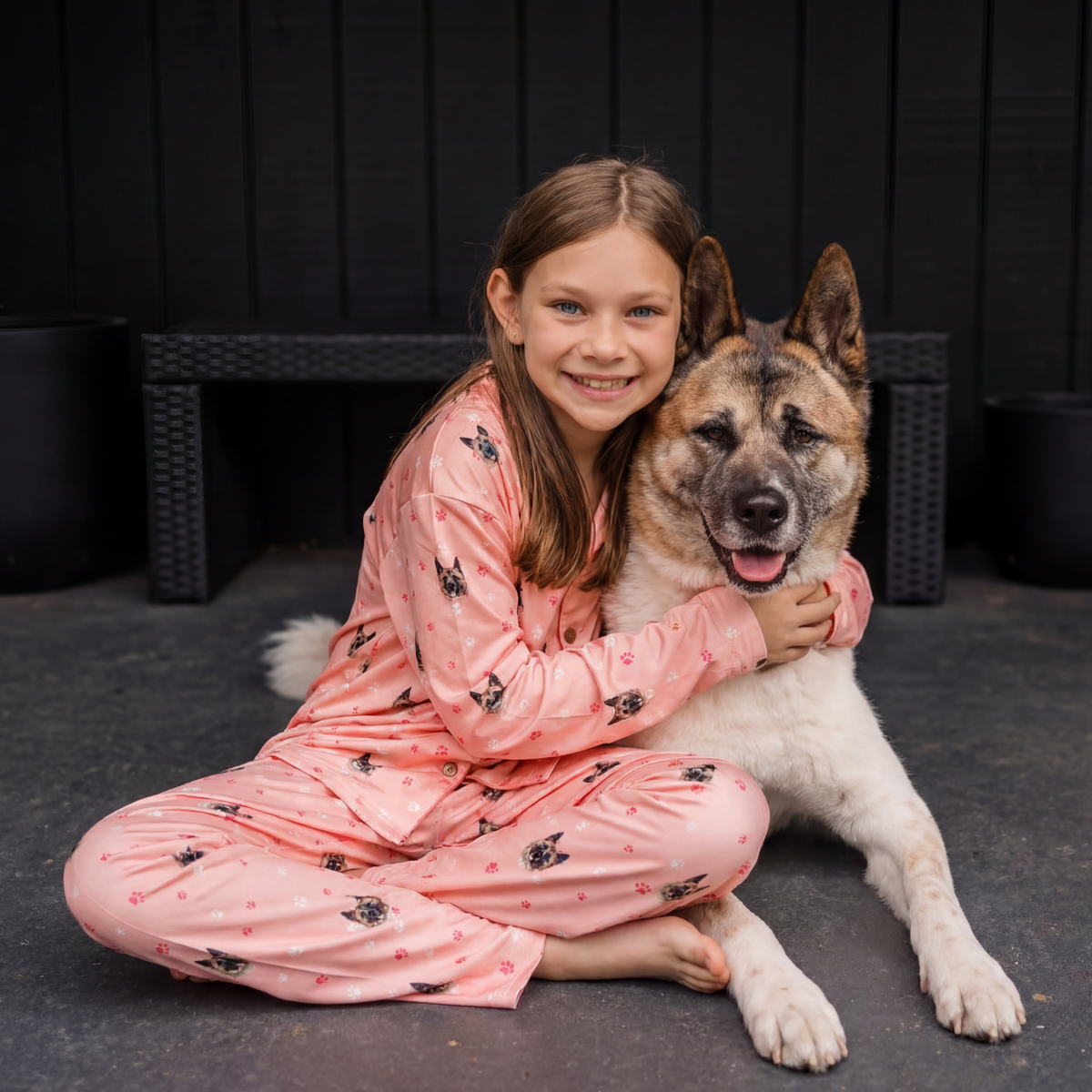 Girl with dog pattern pajama sitting with dog