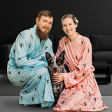Two people in patterned robes with a dog on a dark background